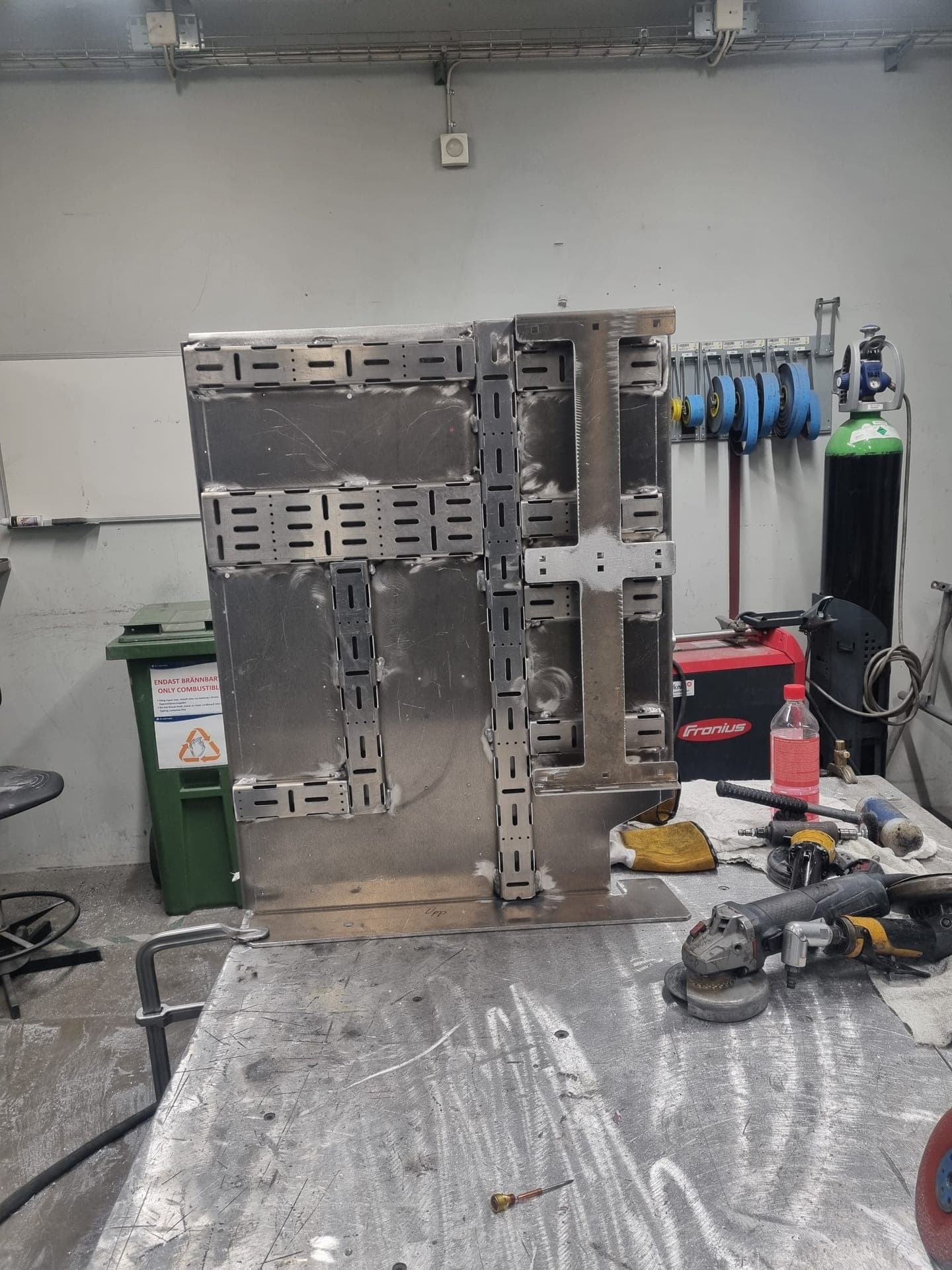 Aluminiumkonsol med kabelstegar på svetsbordet, med Fronius-svets bredvid